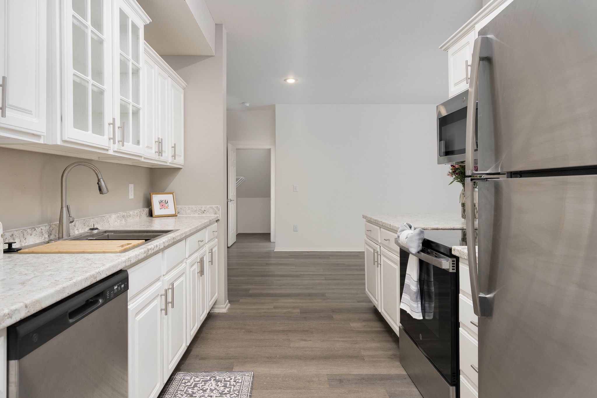 A kitchen with white cabinets and a black fridge.